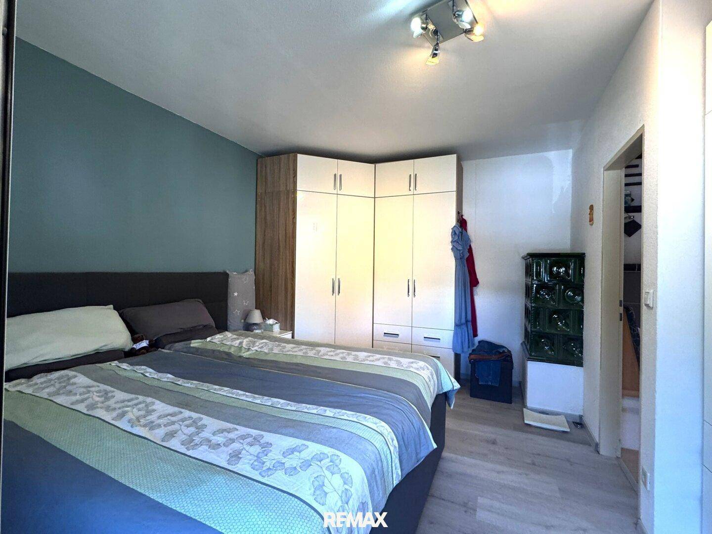 Schlafzimmer mit Doppelbett, Einbauschrank und einem traditionellen grünen Kachelofen.