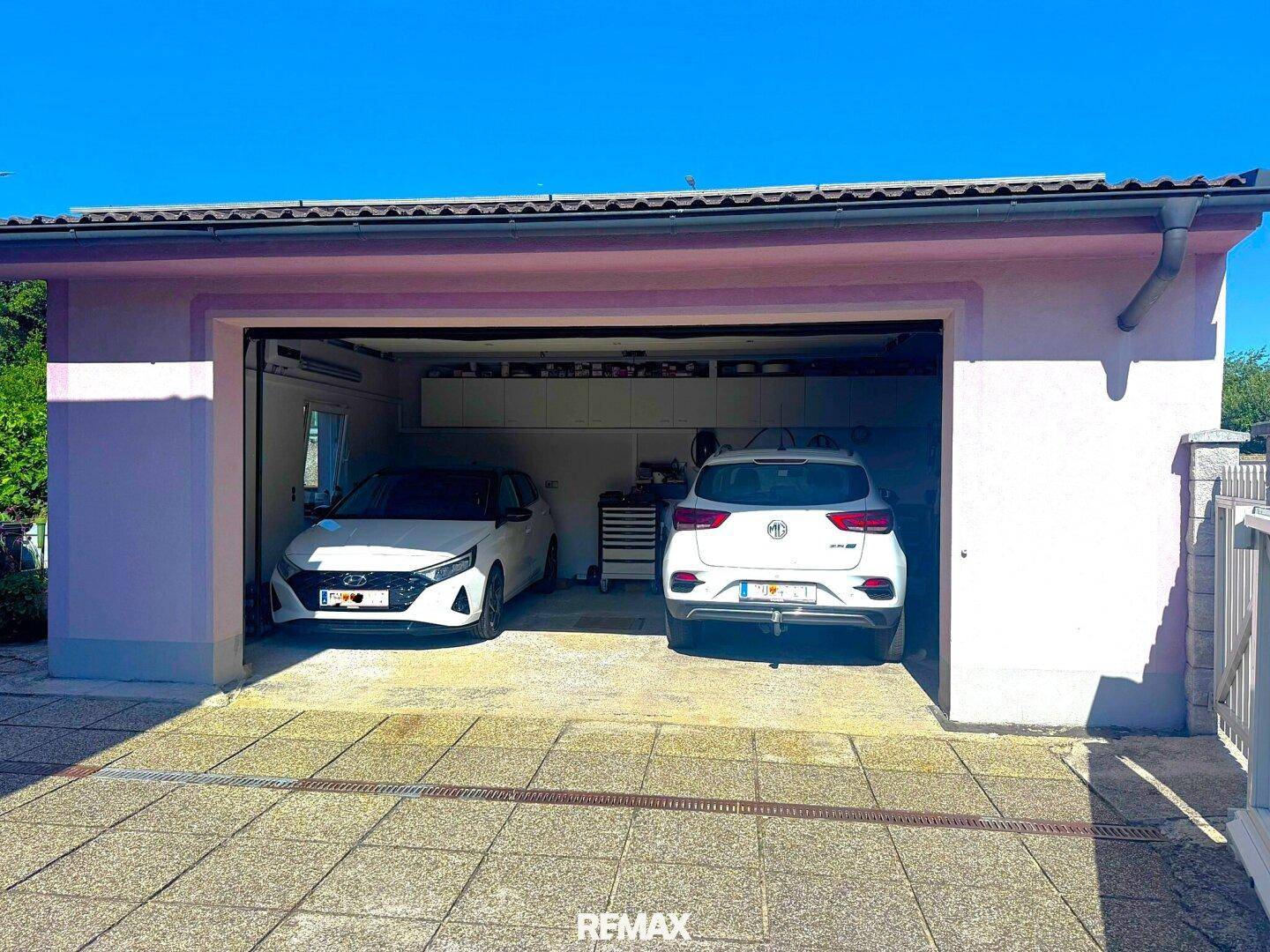 Doppelgarage mit zwei geparkten Autos und Stauraum im hinteren Bereich des Gebäudes.