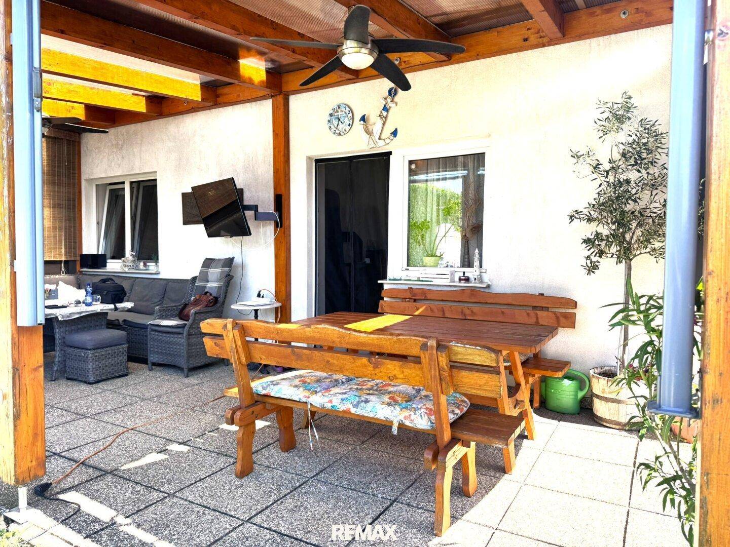 Überdachte Terrasse mit Holzbalken, Essbereich und Blick in den grünen Garten.