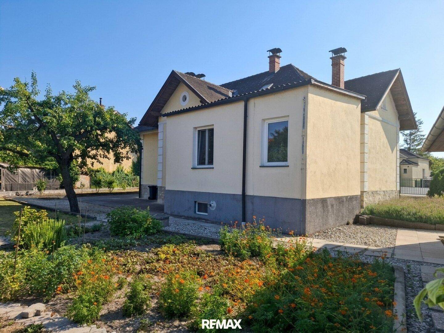 Seitenansicht des Hauses mit blühendem Gartenbereich und gepflegter Grünfläche.