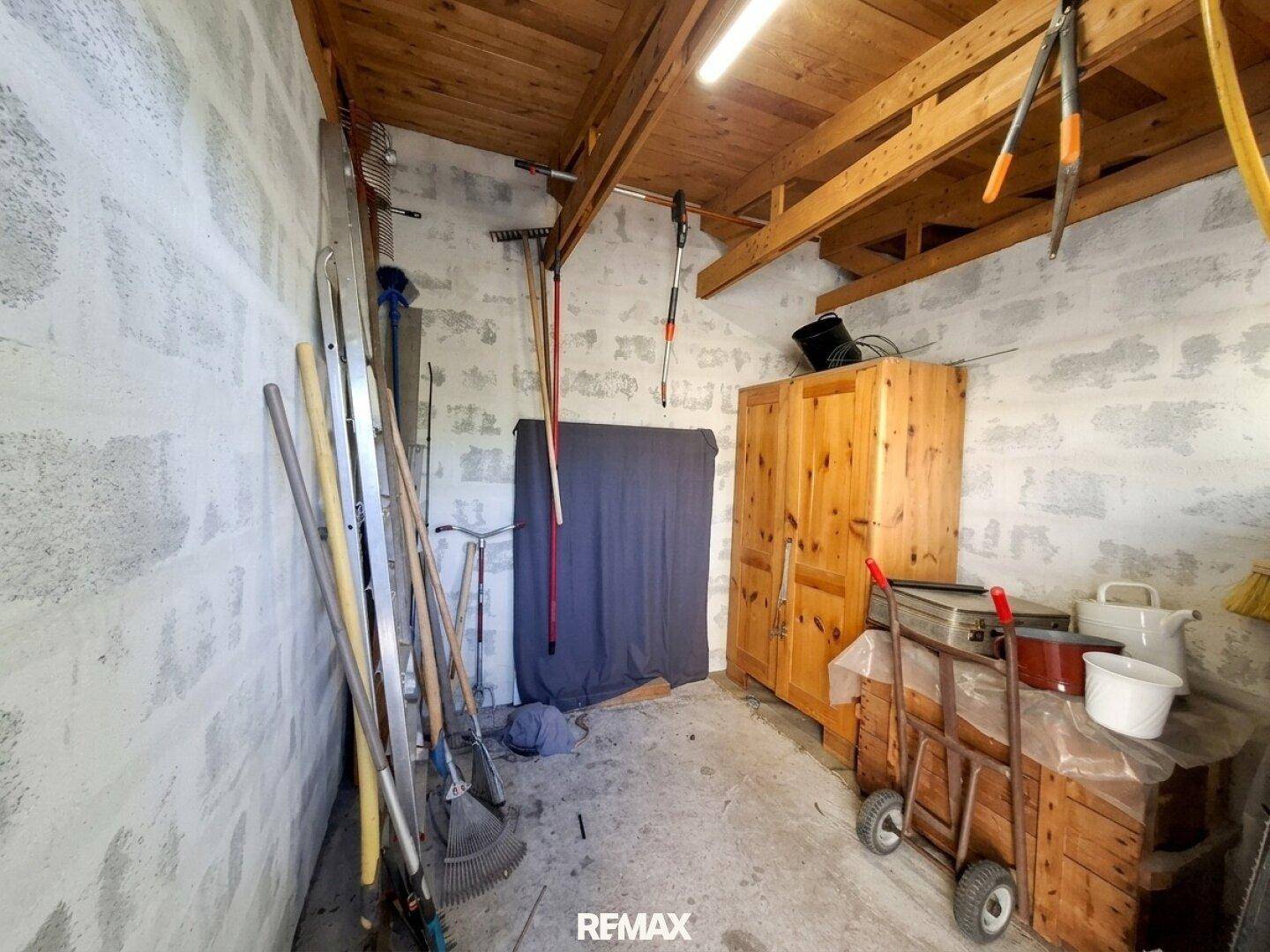Praktischer Abstellraum oder Werkstatt mit Werkzeugen, Holzschrank und Betonwänden.