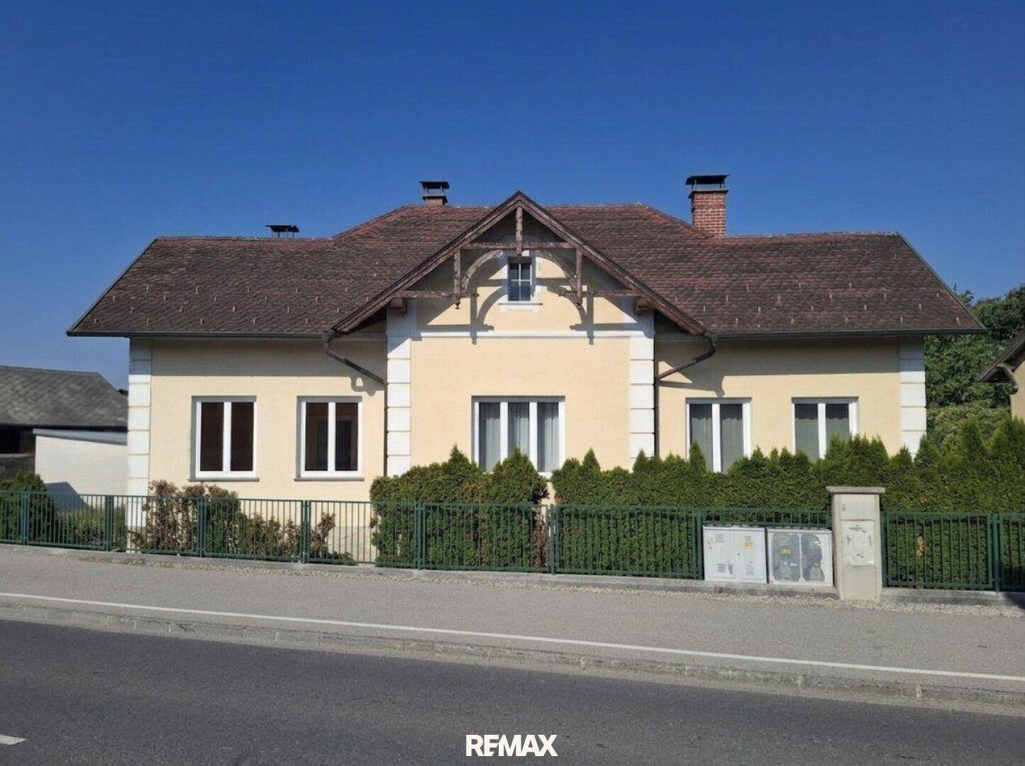 Vorderansicht des Hauses von der Straße aus mit gepflegter Hecke und Fenstern.