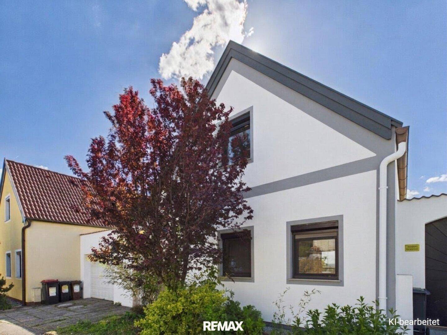 Seitenansicht des Hauses mit Fenstern, Dach und einem Baum im Vordergrund.