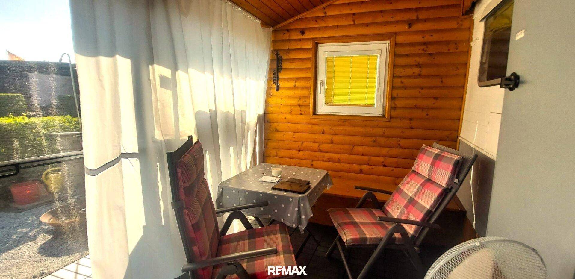 Überdachte Terrasse mit Holzverkleidung und Gartenmöbeln für entspannte Stunden im Freien.