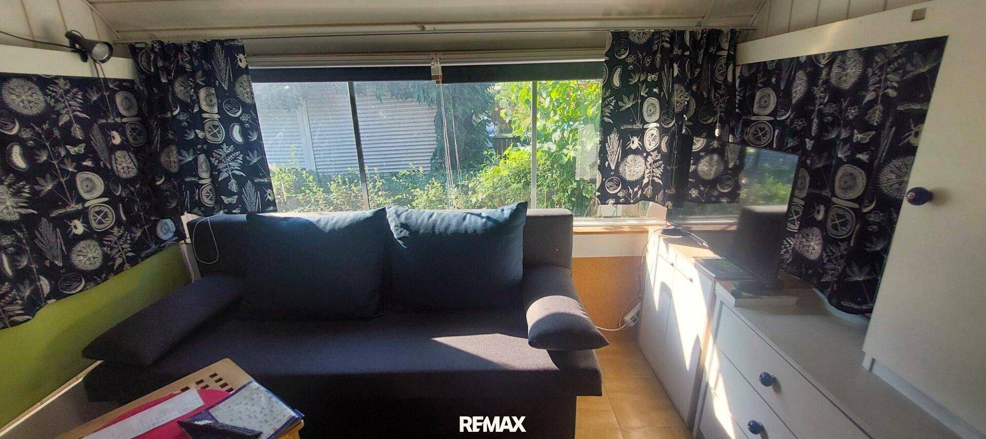 Heller Wohnbereich mit bequemer Couch und großen Fenstern zum Garten, viel Tageslicht.