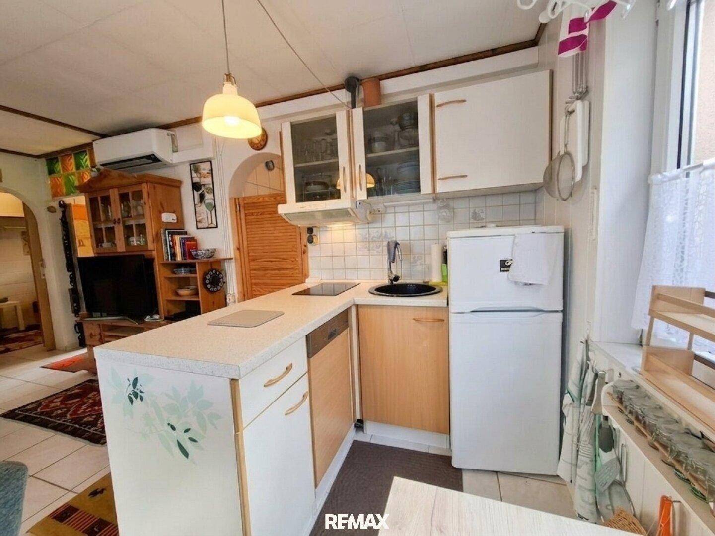 Funktionale Küche mit weißen Schränken, Spüle und Kühlschrank, Teil des offenen Wohnbereichs.