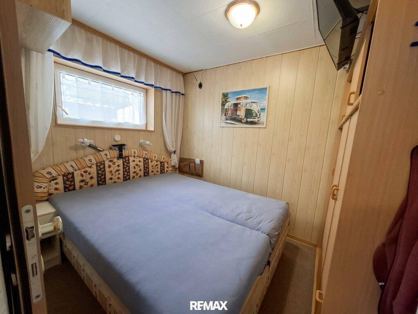 Schlafzimmer mit Doppelbett, Holzvertäfelung an den Wänden und einem Fenster.