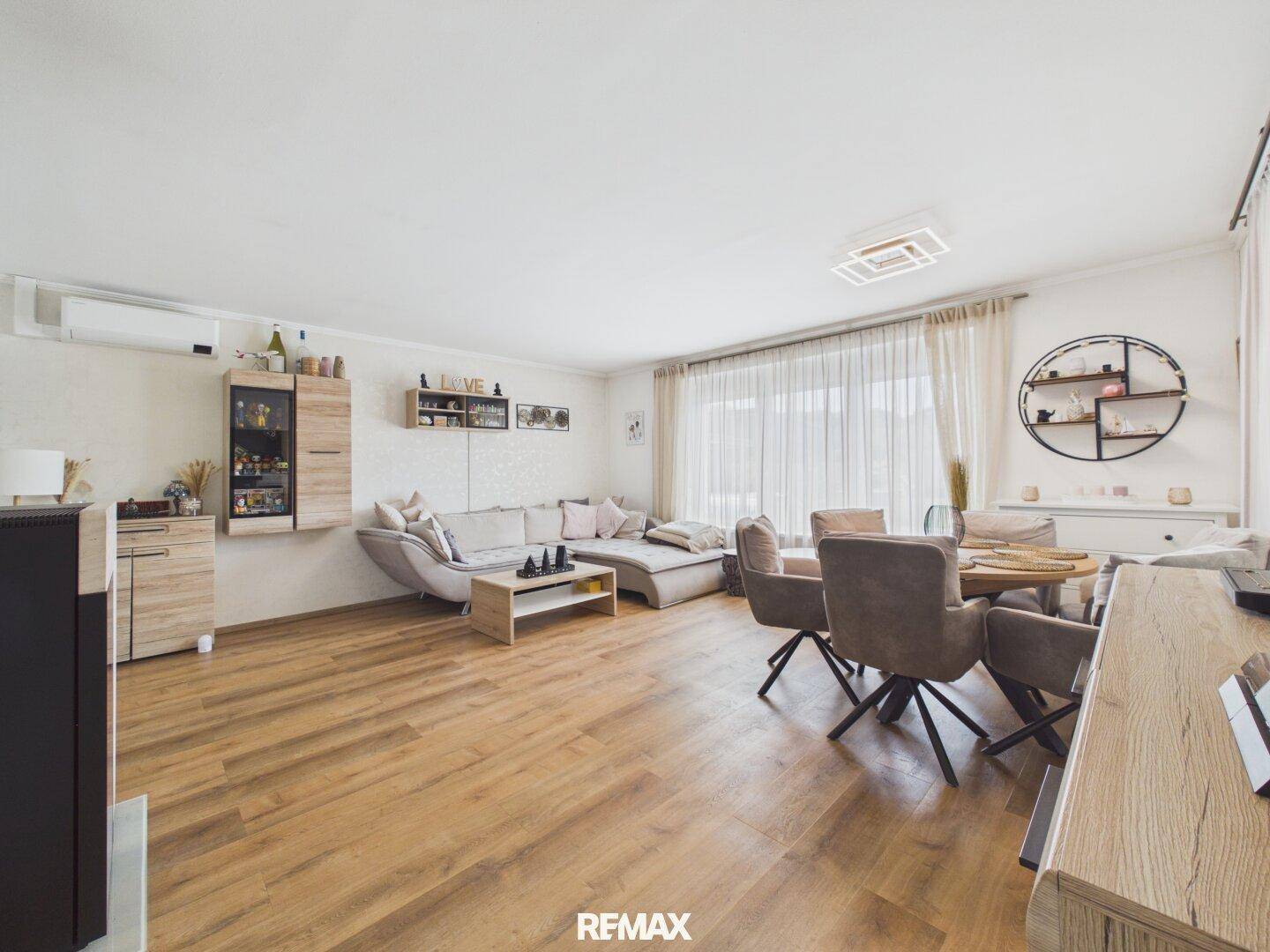 Offener Wohn- und Essbereich mit Holzboden, bequemer Couch und modernem Esstisch.
