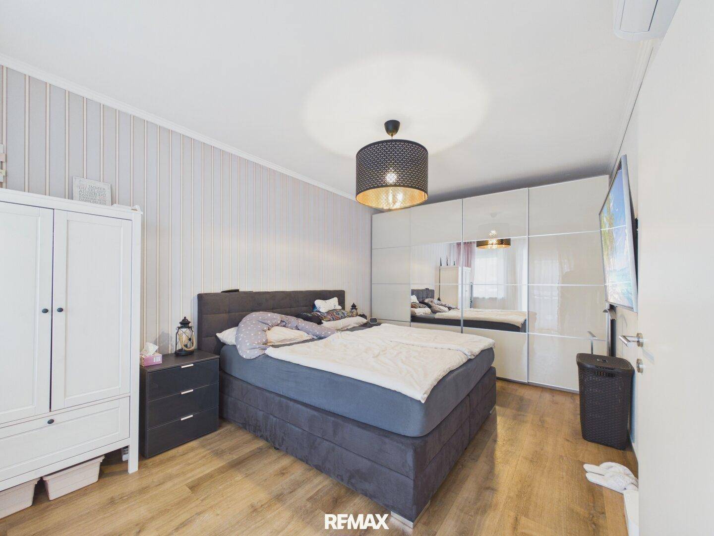 Geräumiges Schlafzimmer mit Doppelbett, Spiegelschränken und Holzboden in hellem Design.