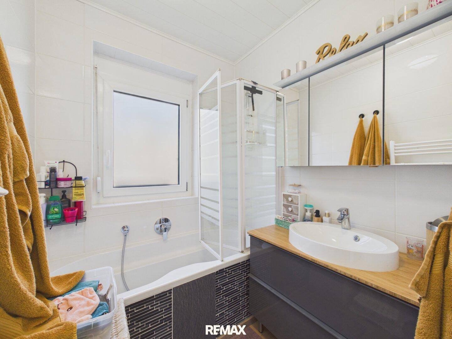 Modernes Badezimmer mit Badewanne, Duschkabine, Einzelwaschbecken und Fenster.