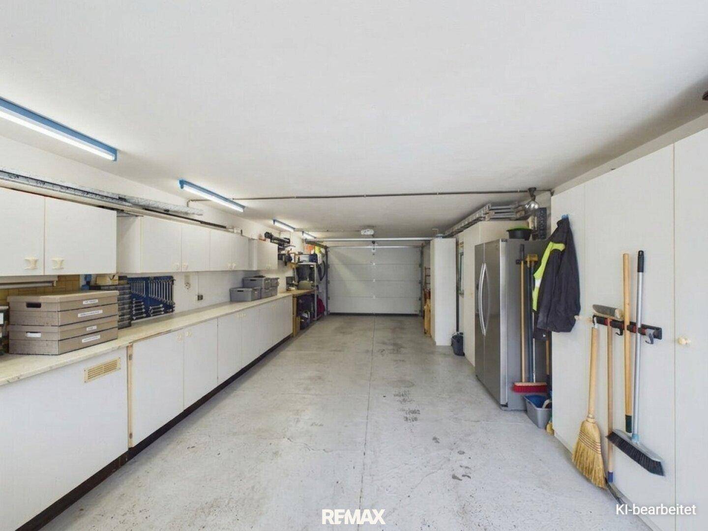 Geräumige Garage mit viel Stauraum, Werkbänken und Zugang zum Außenbereich.