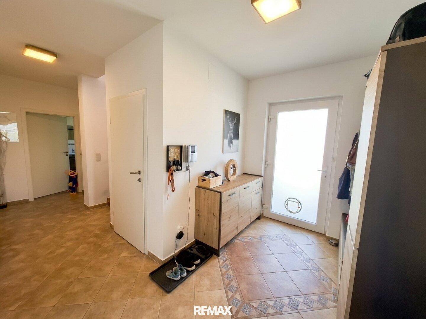 Heller Eingangsbereich mit Fliesenboden und Garderobe, der zu weiteren Räumen führt.