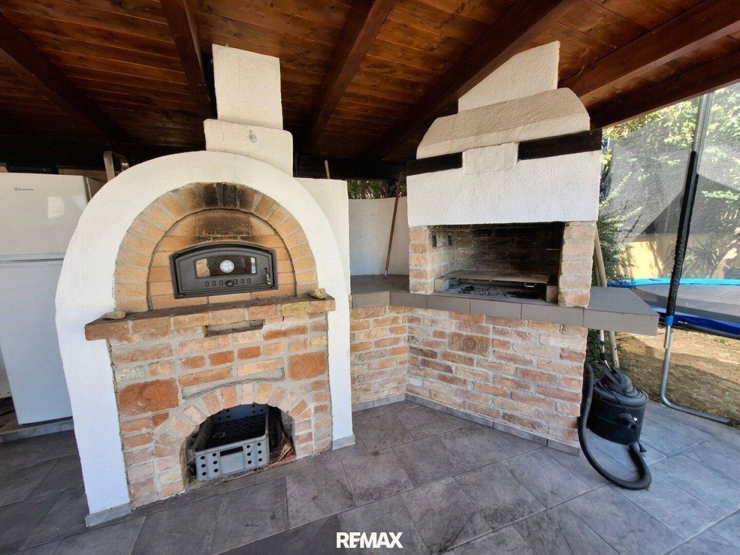 Gemauerter Pizzaofen und Grillbereich im Freien unter einer Holzdecke, perfekt für Kochabende.