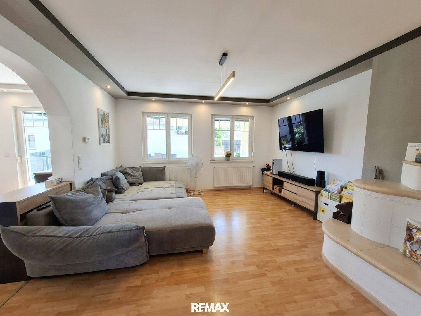 Gemütliches Wohnzimmer mit großem Ecksofa, Parkettboden und Fernseher an der Wand.