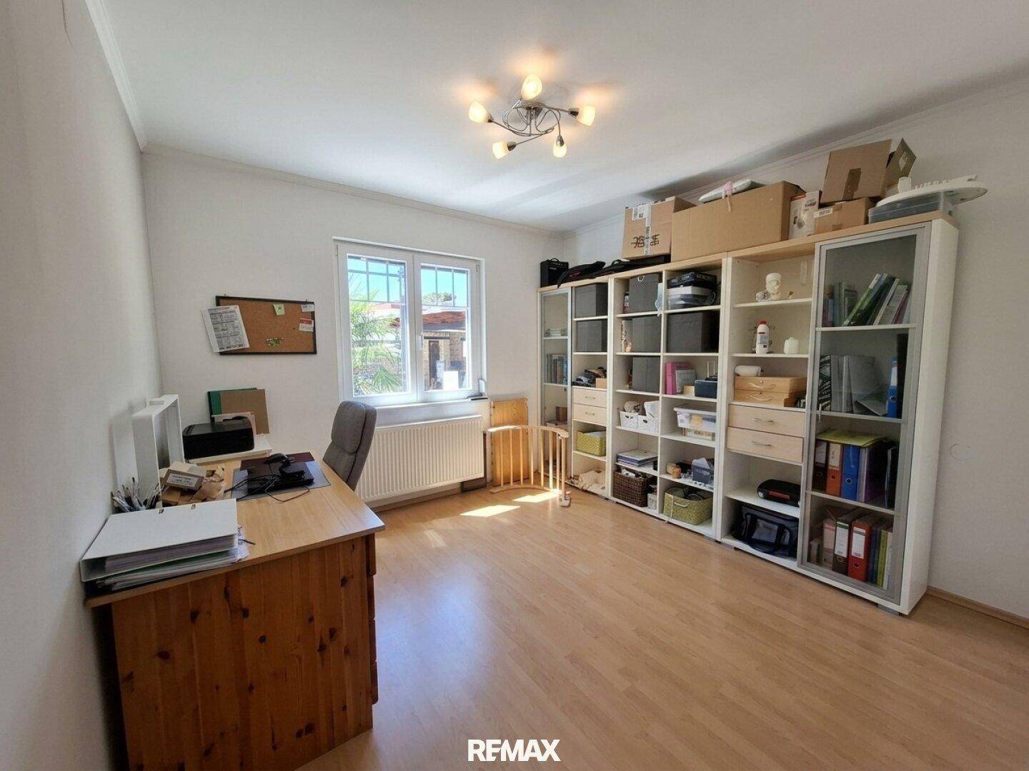 Helles Arbeitszimmer mit Holzschreibtisch, Bücherregalen und Blick ins Grüne.