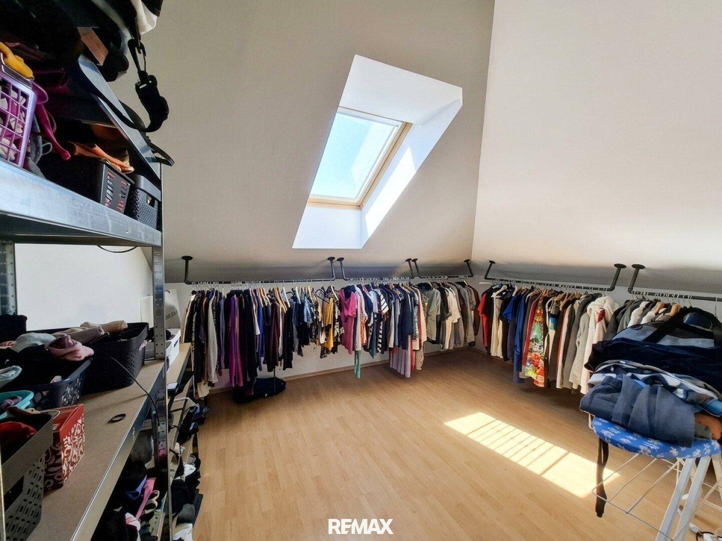 Begehbarer Kleiderschrank im Dachgeschoss mit viel Stauraum und Dachfenster.
