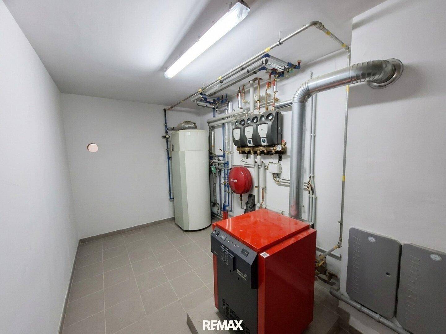 Heizungsraum mit moderner Heizungsanlage, Warmwasserspeicher und sichtbaren Leitungen.