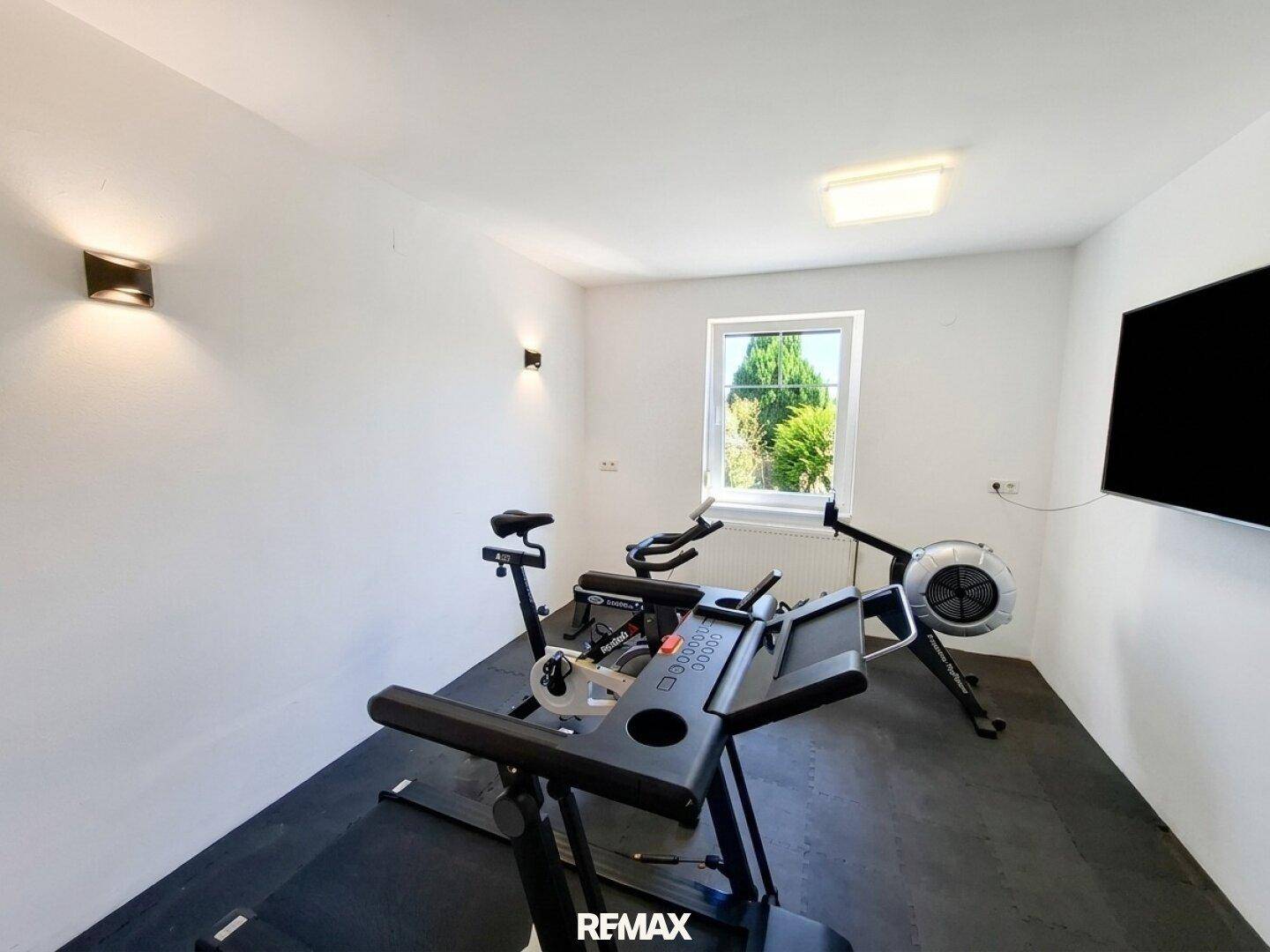 Fitnessraum mit verschiedenen Trainingsgeräten und Blick ins Grüne, ideal für Sportbegeisterte.