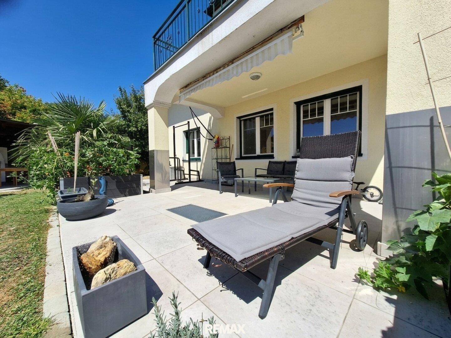 Gemütliche Terrasse mit Sonnenliege und Pflanzen, ideal zum Entspannen im Freien.