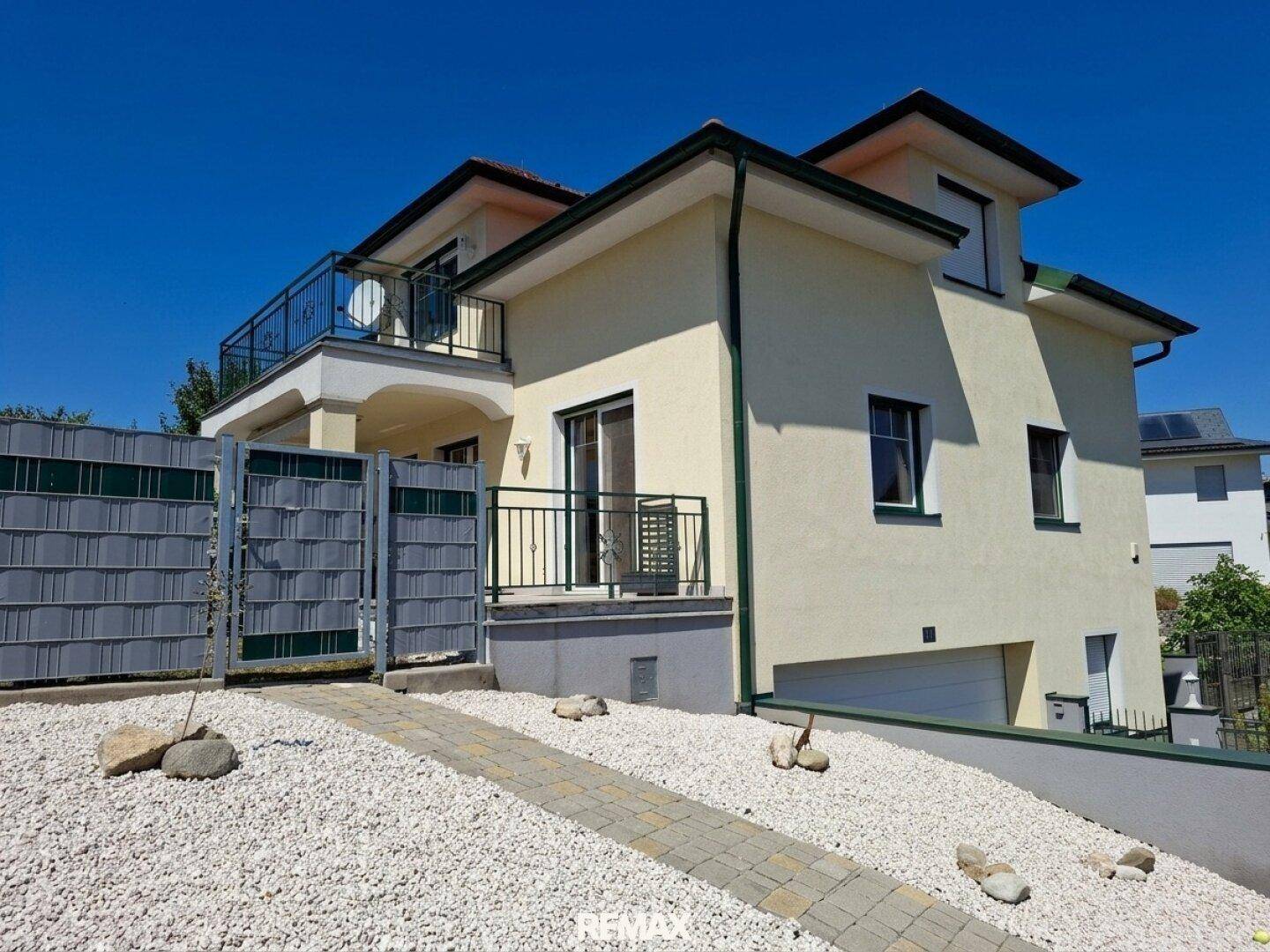 Seitenansicht des Hauses mit Zufahrt zur Garage und einem kleinen Vorgartenbereich.