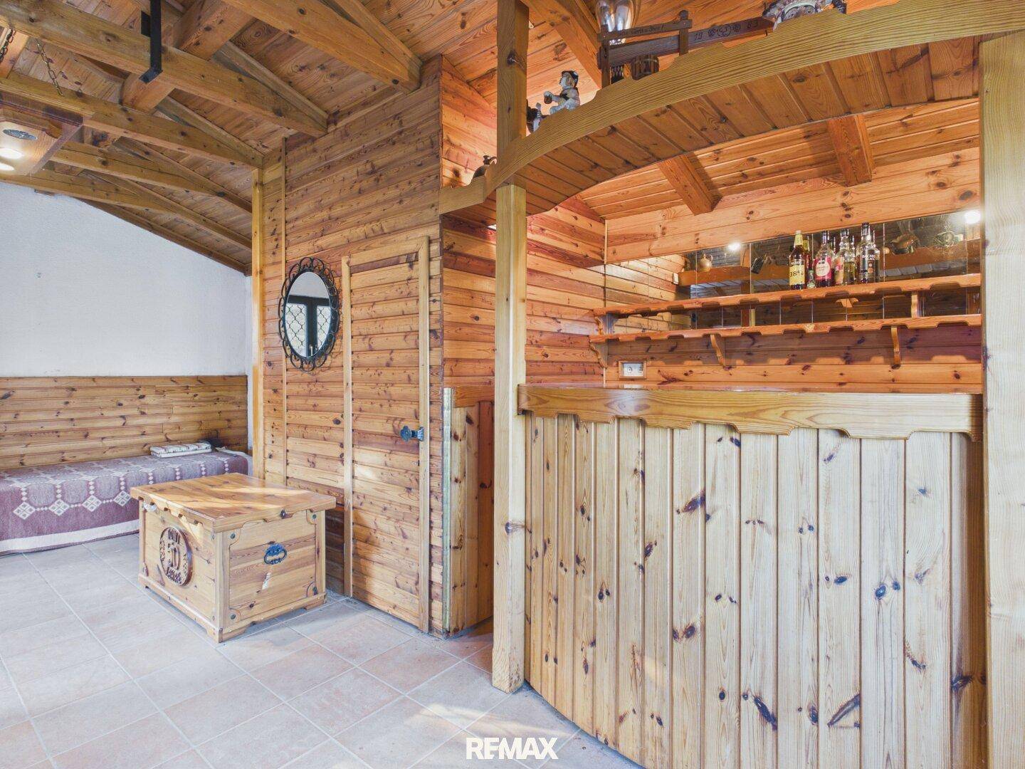 Innenraum mit rustikaler Holzverkleidung, einer Bar und einem kleinen Holztisch.