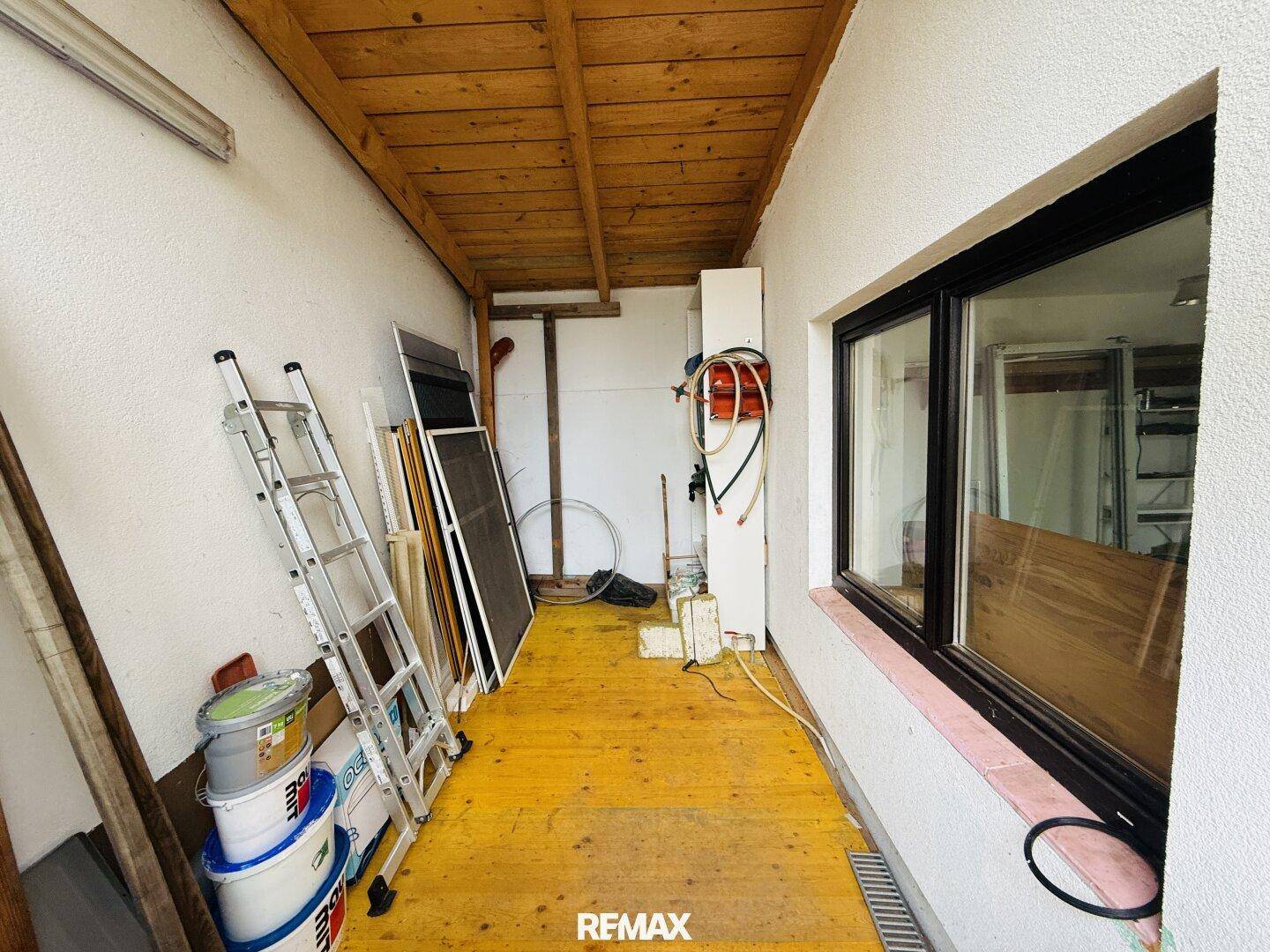 Abstellraum oder Hauswirtschaftsraum mit Holzdecke, Fenster und verschiedenen Lagergegenständen.