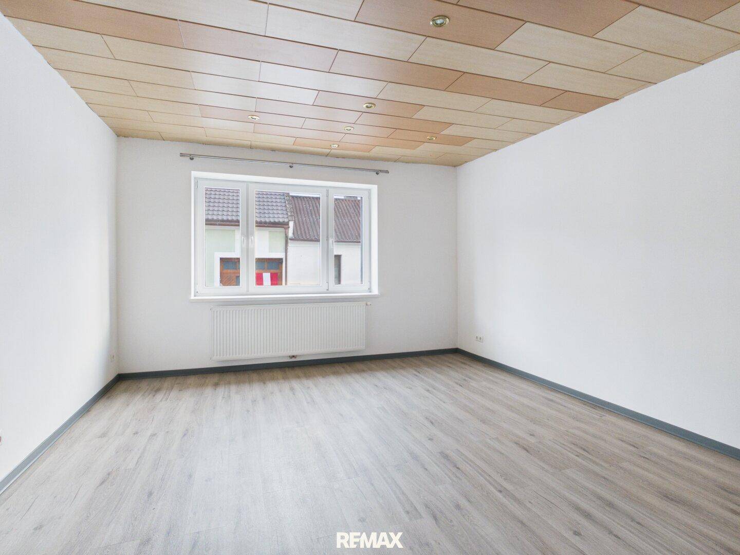 Helles Schlafzimmer mit dekorativer Holzdeckenverkleidung und Laminatboden.