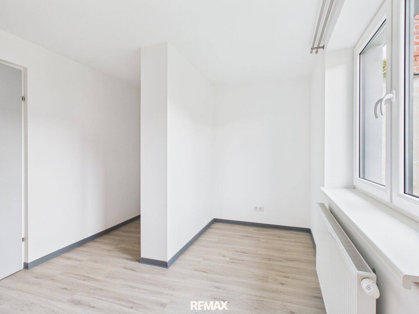 Heller Wohnraum mit Laminatboden und Fenster, ideal für individuelle Einrichtungsideen.