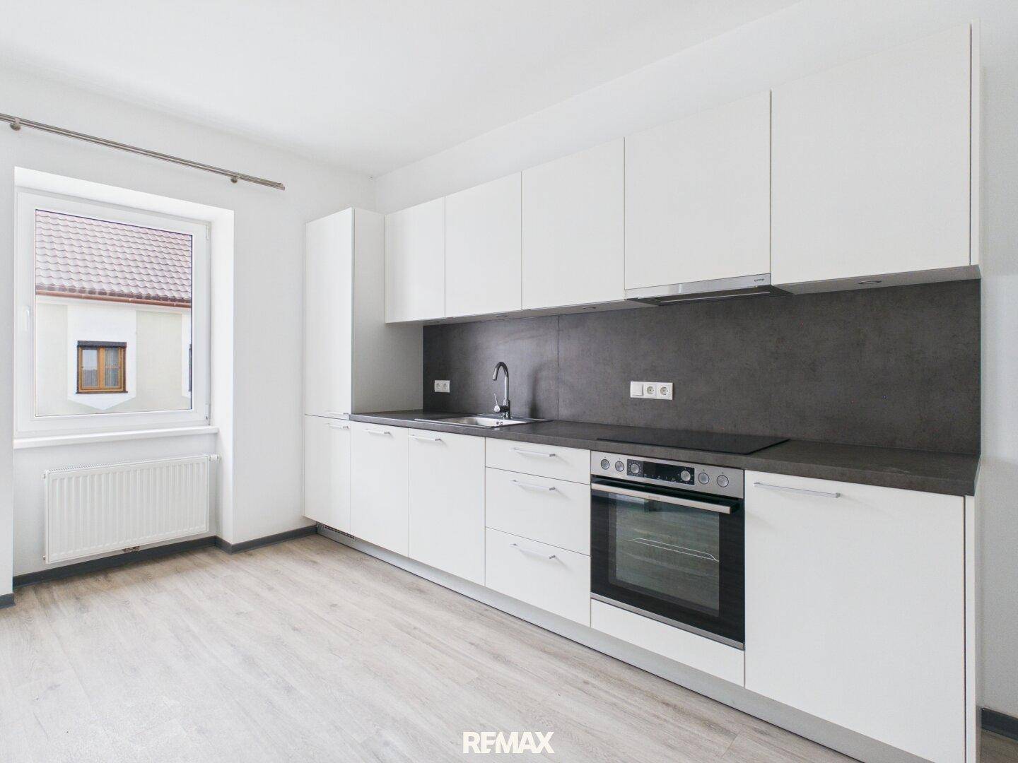 Neue, moderne Einbauküche mit weißen Schränken, Induktionskochfeld und Backofen.