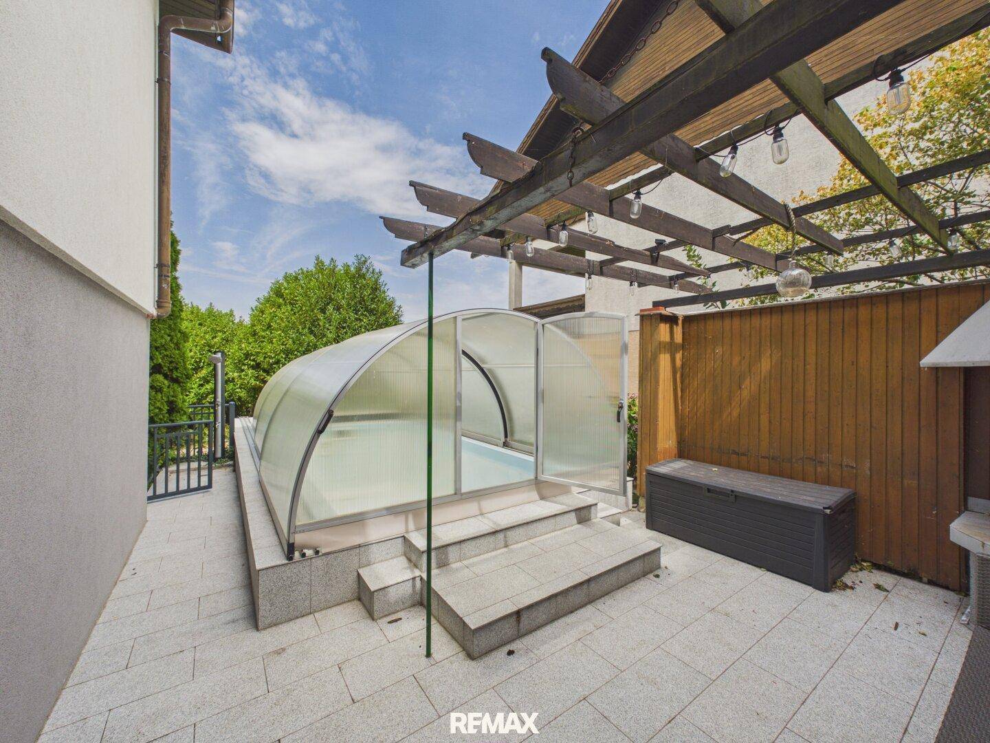 Terrasse mit überdachtem Pool und Pergola, ideal für Entspannung im Freien.