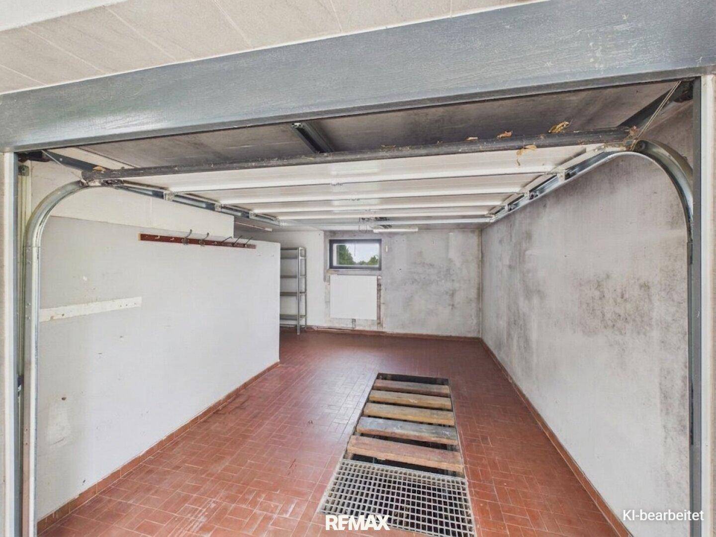 Geräumige Garage mit Fliesenboden und Grube für Fahrzeugwartung.
