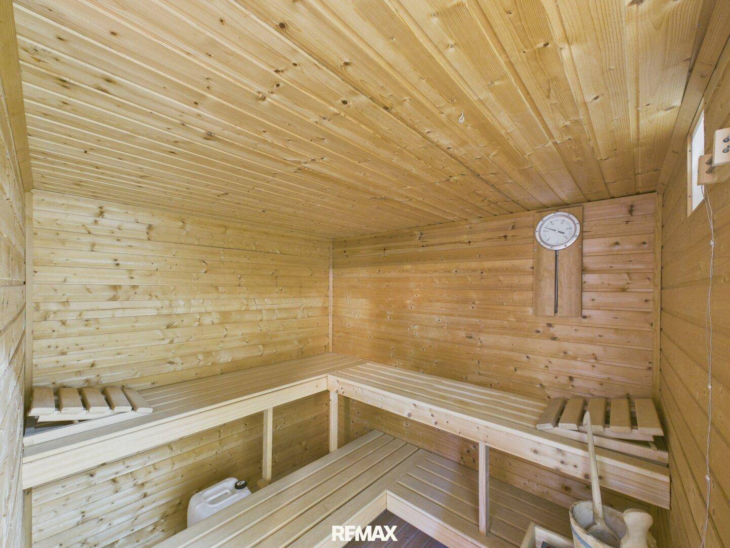 Holzvertäfelte Sauna mit Bänken und Thermometer, bereit zur Entspannung.
