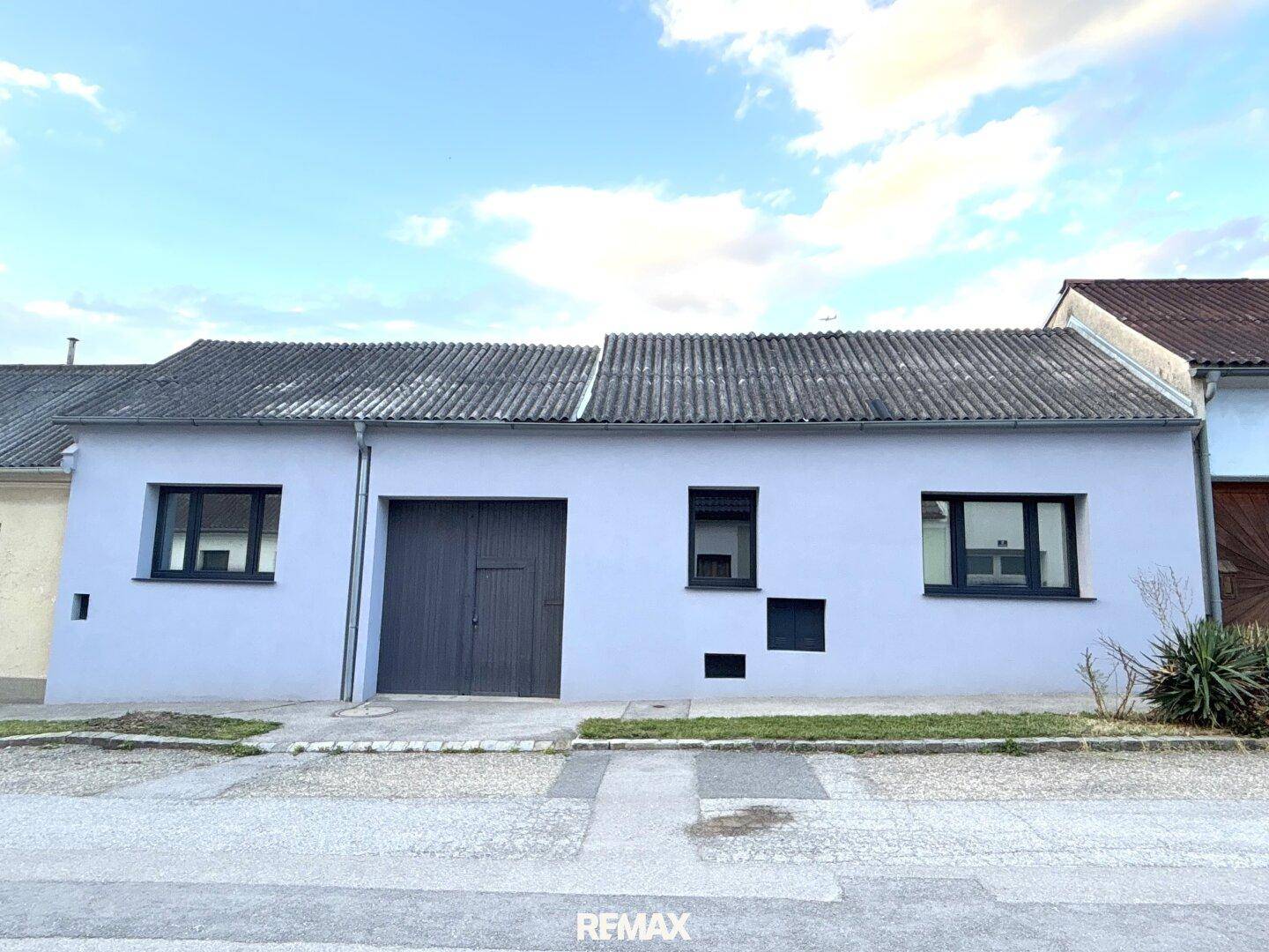 Vorderansicht des Hauses mit Garage und schlichter, modernisierter Fassade.
