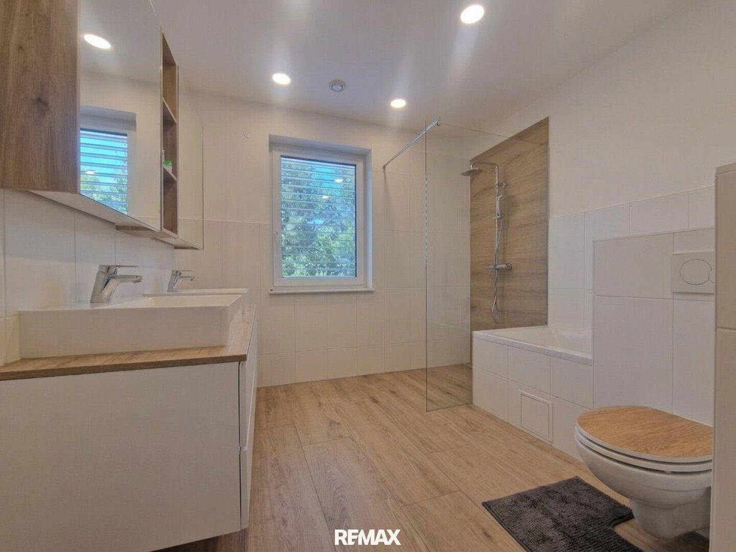 Modernes Badezimmer mit Doppelwaschbecken, begehbarer Dusche und Badewanne.