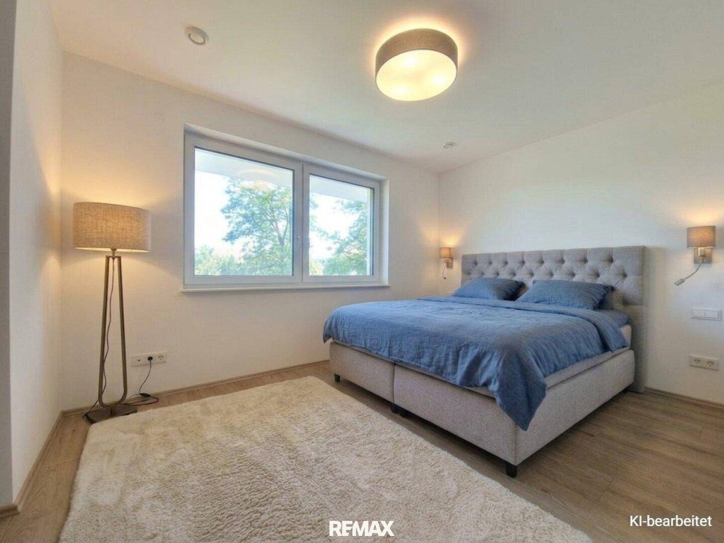 Helles Schlafzimmer mit großem Doppelbett, Teppich und Blick ins Grüne.