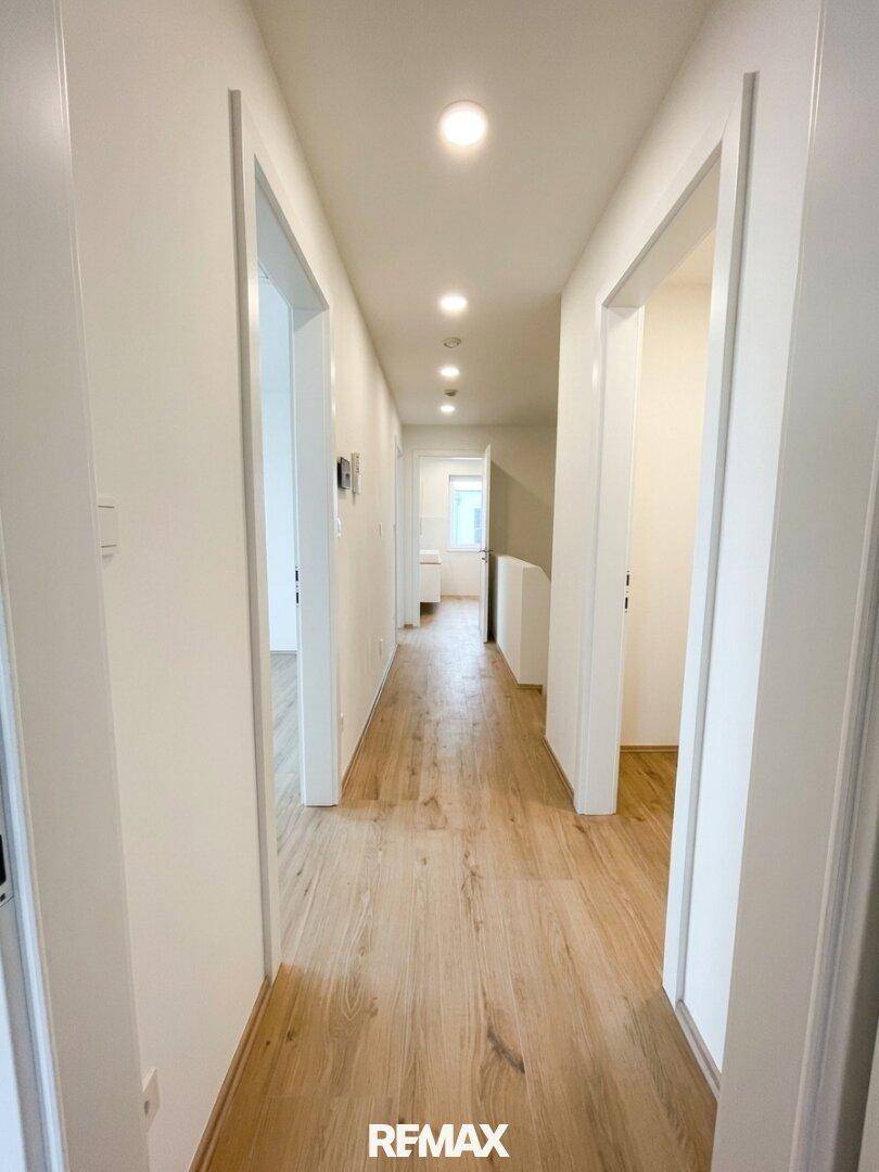Langer, heller Flur mit modernem Laminatboden und Einbaustrahlern in der Decke.