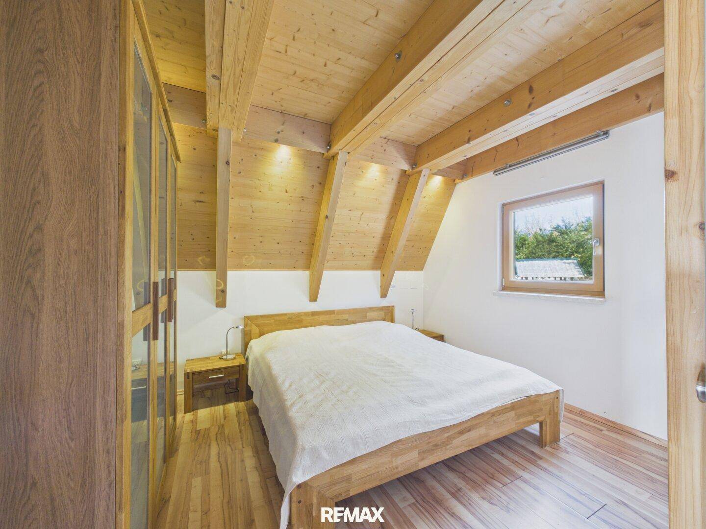 Schlafzimmer mit Holzbalkendecke, Holzboden und einem großen Kleiderschrank.