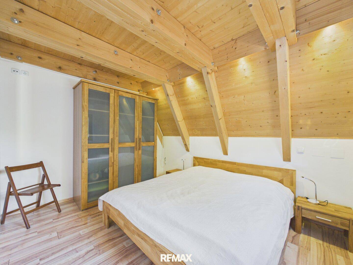 Geräumiges Schlafzimmer mit Holzbalken, Holzboden und einem großen Kleiderschrank.
