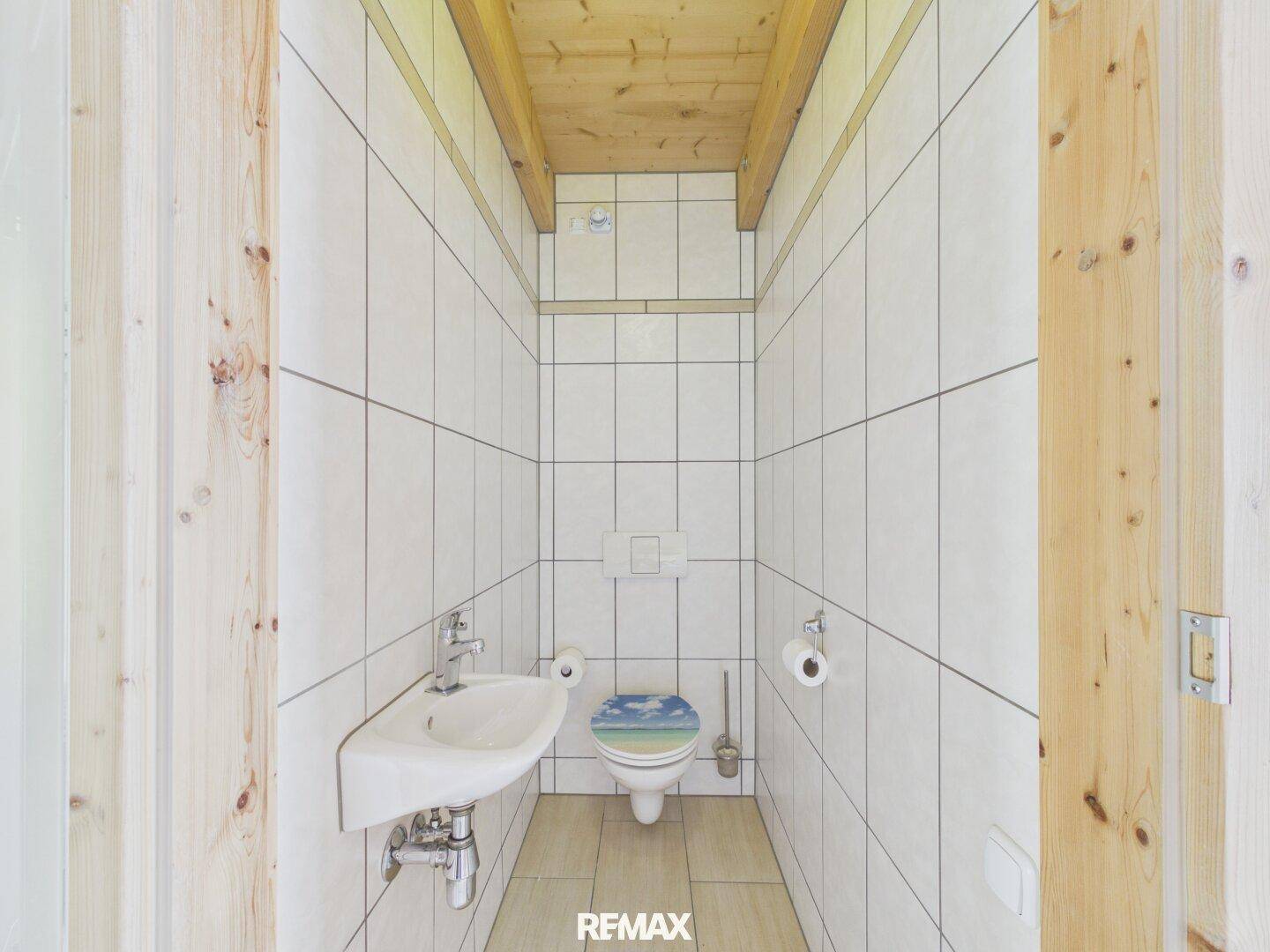 Separates WC mit Wand-WC und kleinem Waschbecken, komplett gefliest.