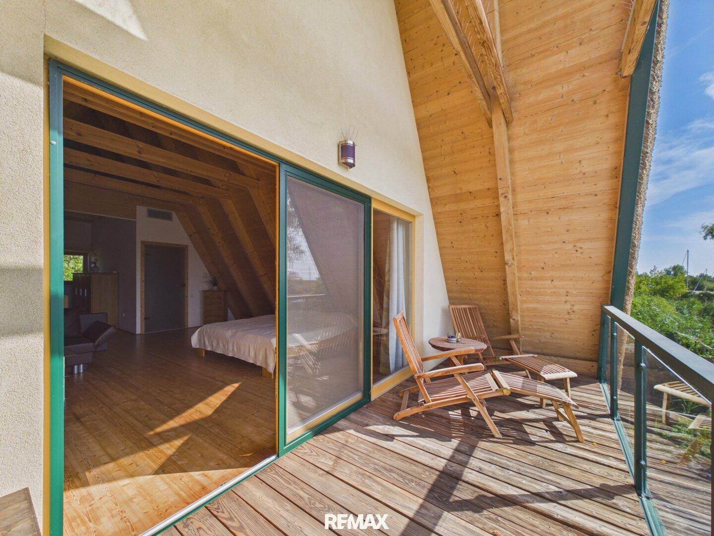 Kleiner Balkon mit Holzmöbeln und Blick ins Grüne, zugänglich vom Schlafzimmer.