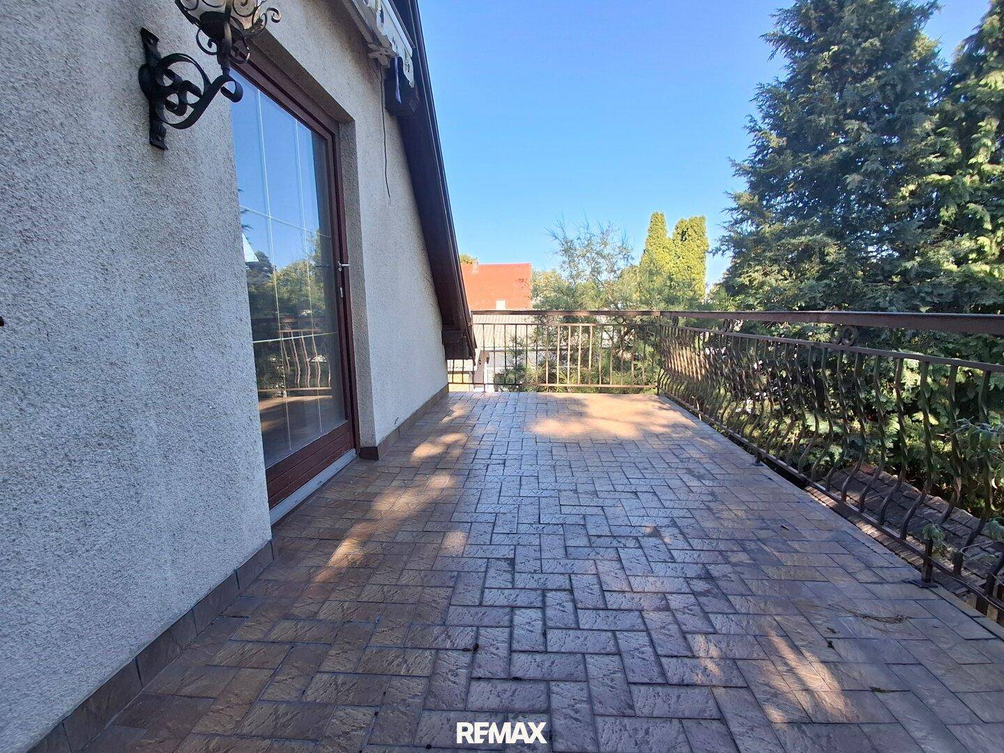 Geräumige Terrasse mit gemustertem Pflaster und schmiedeeisernem Geländer, ideal für Entspannung im Freien.
