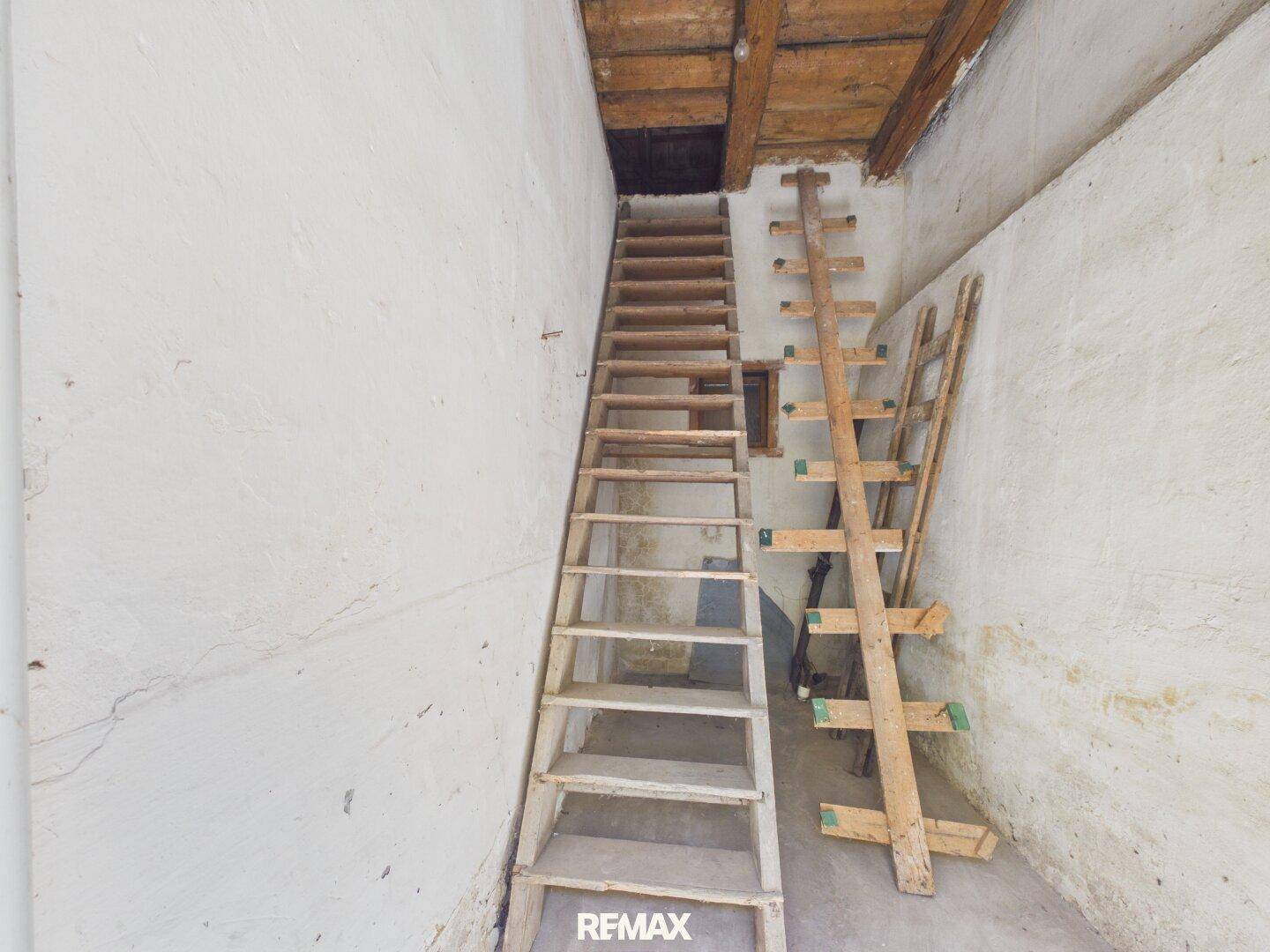 Steile Holztreppe führt zu einem oberen Bereich oder Dachboden, rustikaler Zustand.