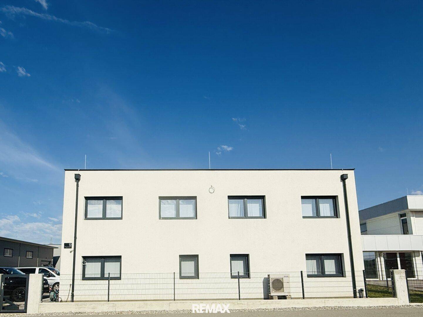 Ansicht der modernen weißen Fassade des Gebäudes unter einem klaren blauen Himmel.