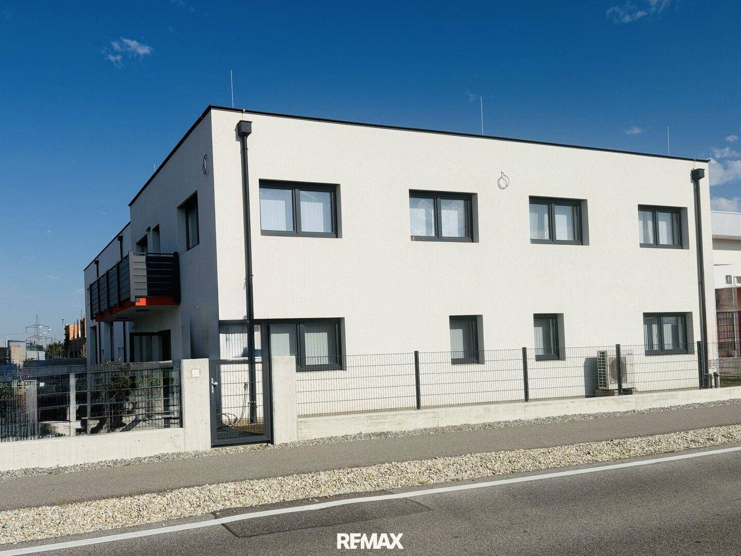 Seitenansicht des modernen Gebäudes mit mehreren Balkonen und einer schlichten weißen Fassade.