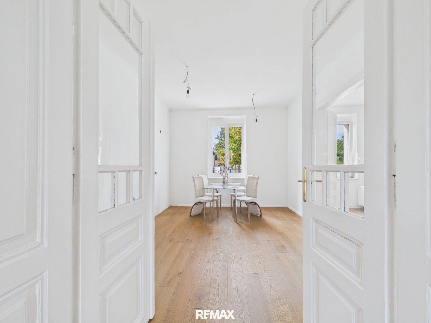Esszimmer mit Holzboden und einem modernen Glastisch, der viel Tageslicht erhält.