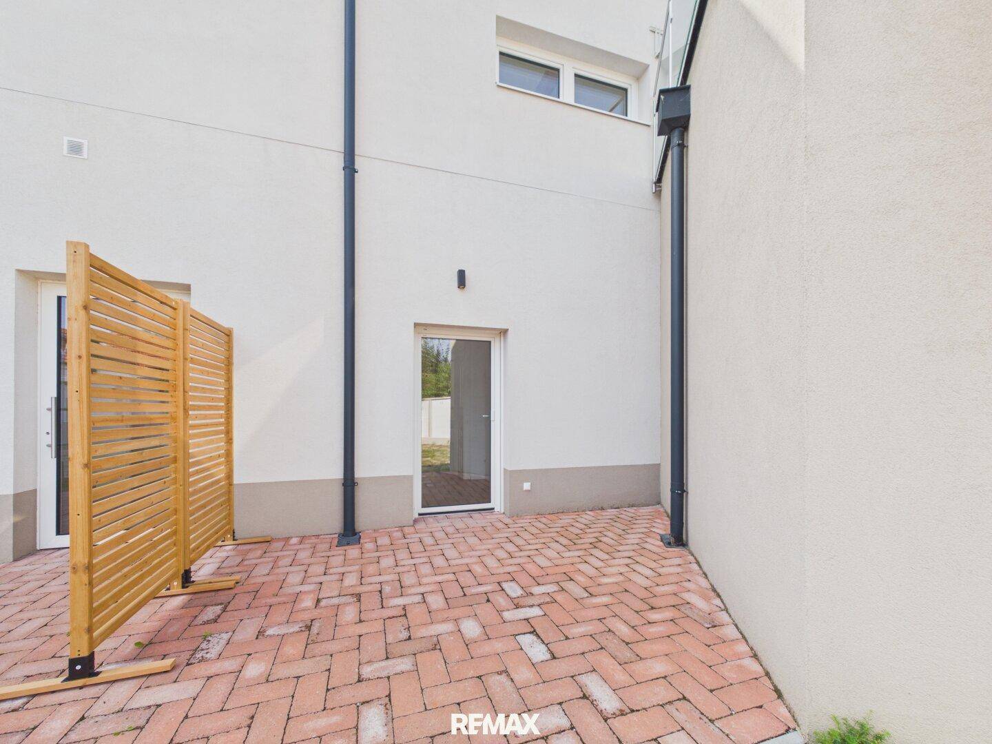 Gepflasterte Terrasse mit Sichtschutz und Zugang zum Gebäude.