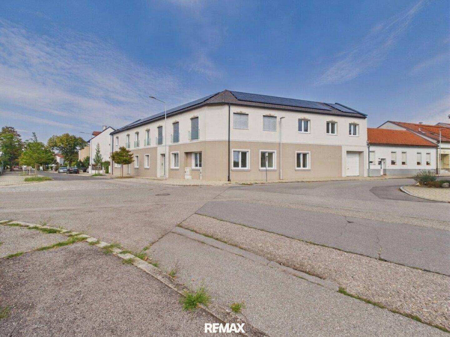 Ansicht des modernen Gebäudes von der Straße mit umliegender Bebauung und blauem Himmel.