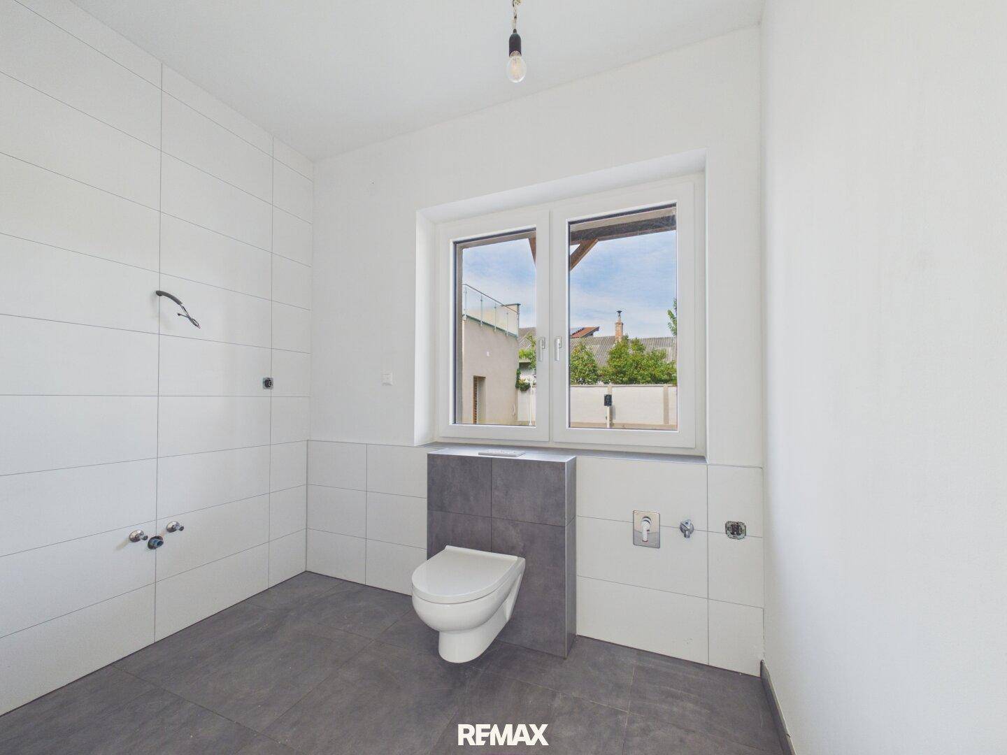Helles Badezimmer im Bau mit wandhängendem WC, modernen Fliesen und Fenster.