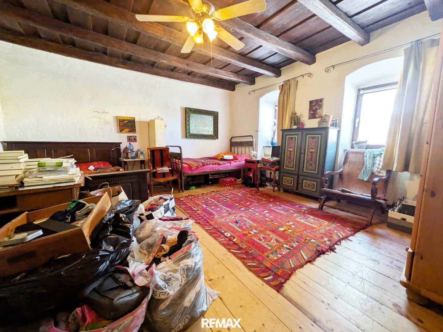 Rustikales Schlafzimmer mit Holzbalkendecke, Dielenboden und traditionellen Möbeln.