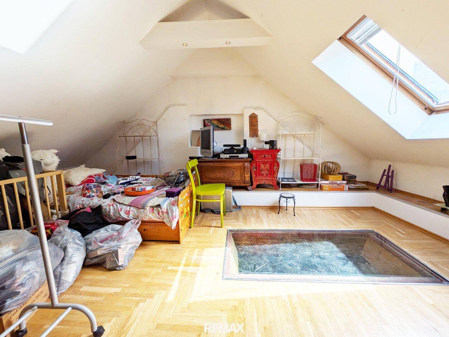 Dachgeschoss-Schlafzimmer mit Holzboden, Dachfenster und einer interessanten Glasbodenplatte.
